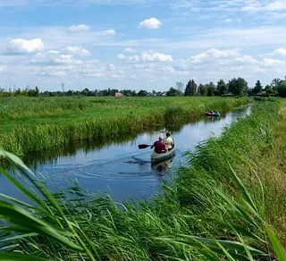 Kano’s op een rustige rivier omgeven door groen landschap en heldere lucht